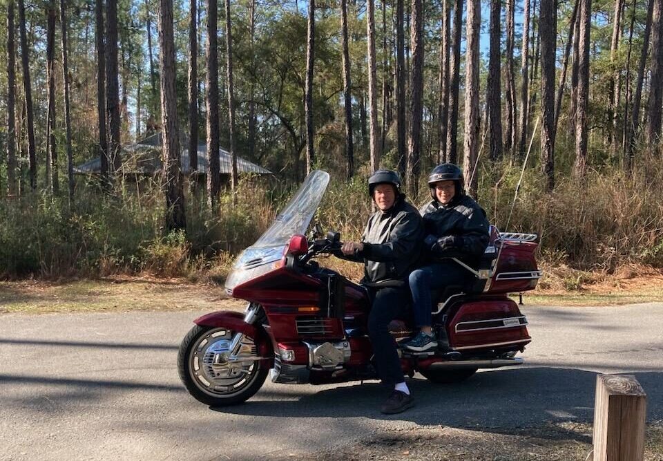 Judi on their motorcycle in the woods