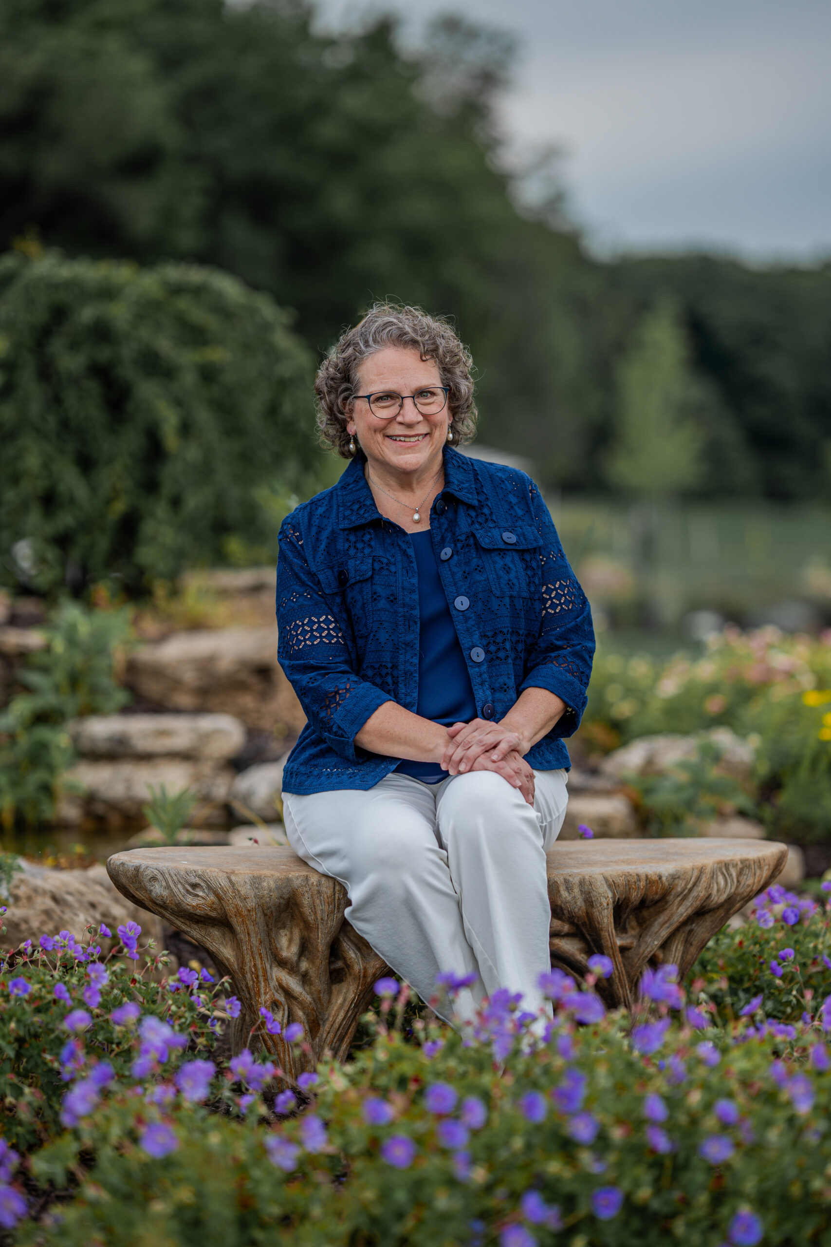 Judi sitting by a waterfall with flowers